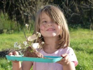 Petite fille portant un plateau de fleurs